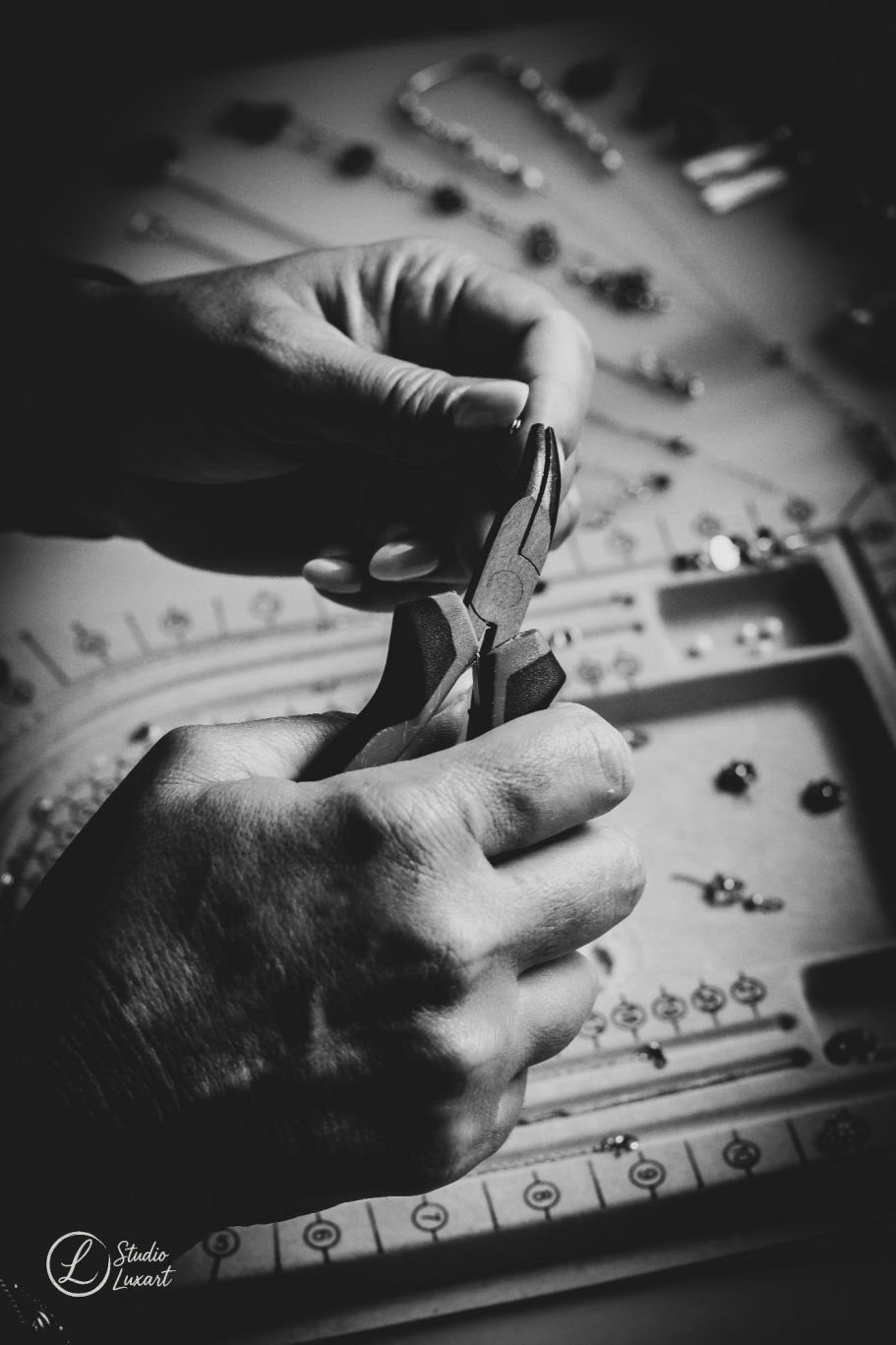 Des mains utilisant une pince pour manipuler des fils sur une table de travail.